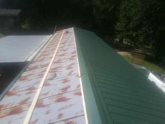 Old rusted panels beside newly installed green metal roofing — Wind Damage Roof Repair by Roofing Brothers in Barnwell