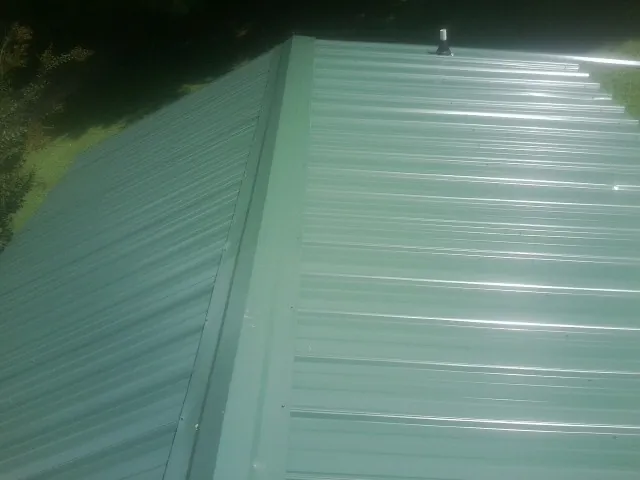 New green metal panels meeting at the ridge of a roof — Flat Roof Repair work by our crew in Barnwell