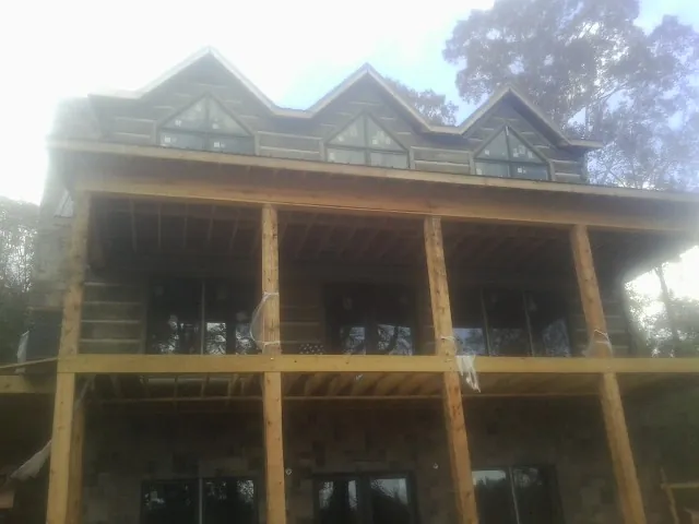 Dormers and porch framing on a large log home under construction — Roof Coating work by our crew in Barnwell
