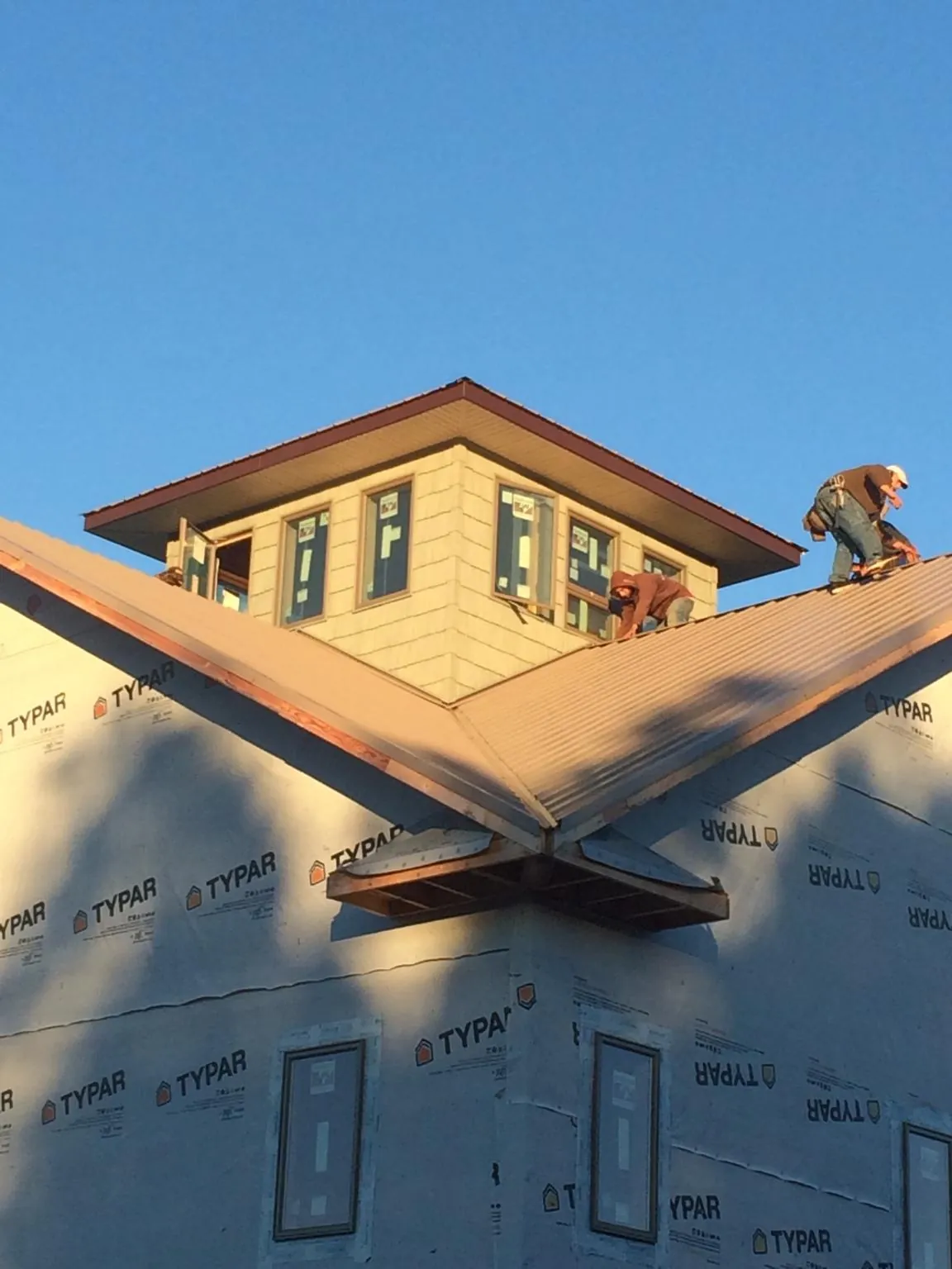 Roofers working around a rooftop cupola on a new metal roof at sunset — Roof Waterproofing in Barnwell by Roofing Brothers